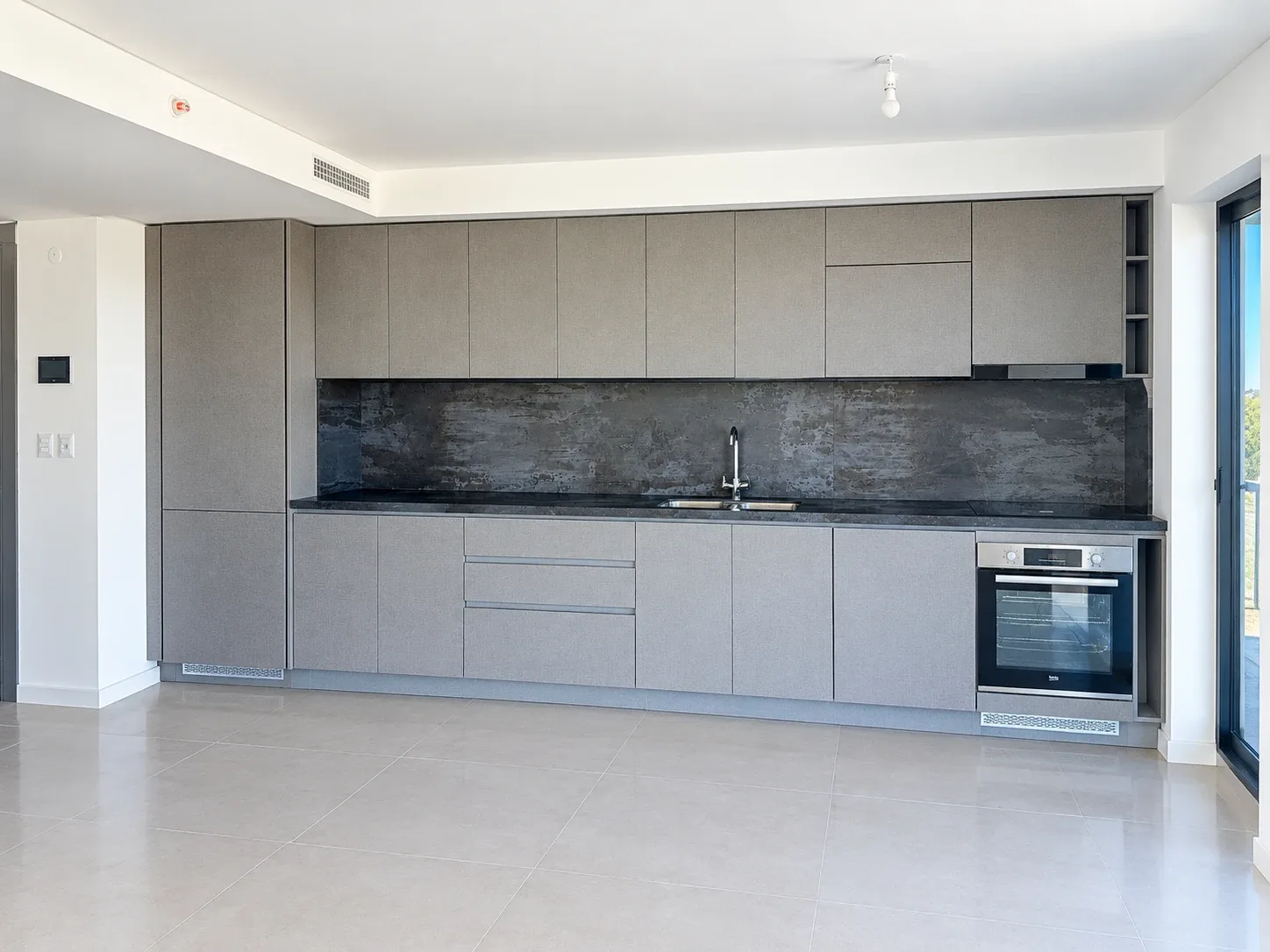 Cocina con muebles grises y mesada oscura